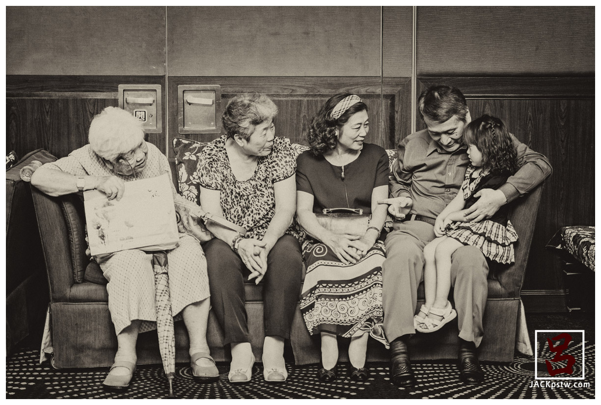 小朋友坐爺爺的大腿上,爺爺在問小妹妹這是誰,看的出來妹妹有點靦腆害羞